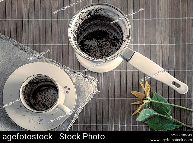 Top view of an empty coffee Cup with coffee stains on the bottom and an empty dirty coffee mug after finishing drinking. A dirty Cup and a Turk on a bamboo...