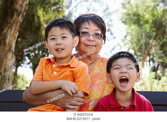 Asian grandmother sitting with grandsons on bench