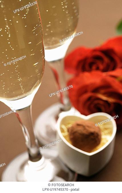 Champagne glasses, roses and a gift box of truffles