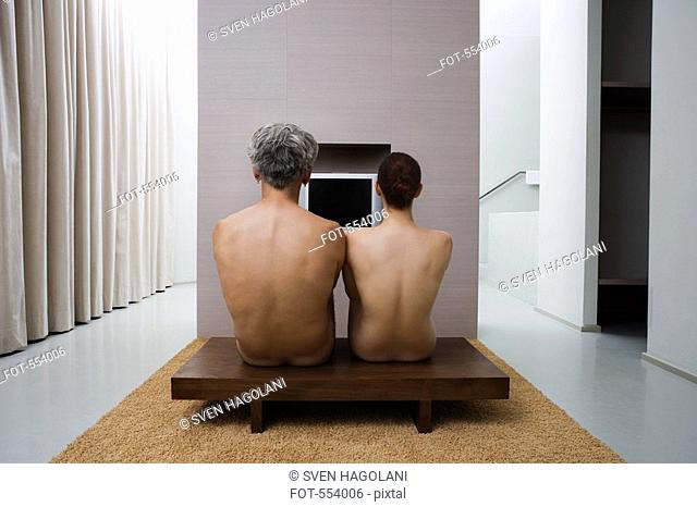 The backs of a naked man and woman sitting