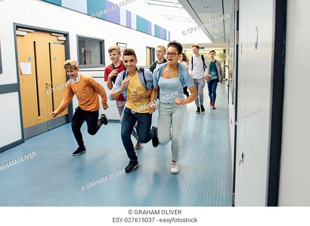 Teen students are running down the corridor of their school, in a rush to leave for the summer holidays