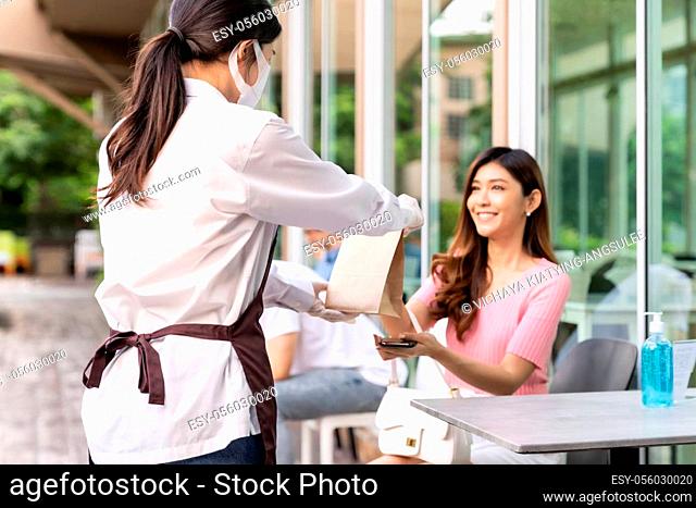 Asian Young adult in car holding disposable bag for take out food from drive thru service restaurant. Drive thru is new normal and popular service after...