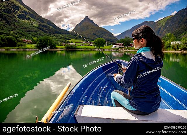 Woman fishing on a boat. Beautiful Nature Norway natural landscape. lovatnet lake Lodal valley