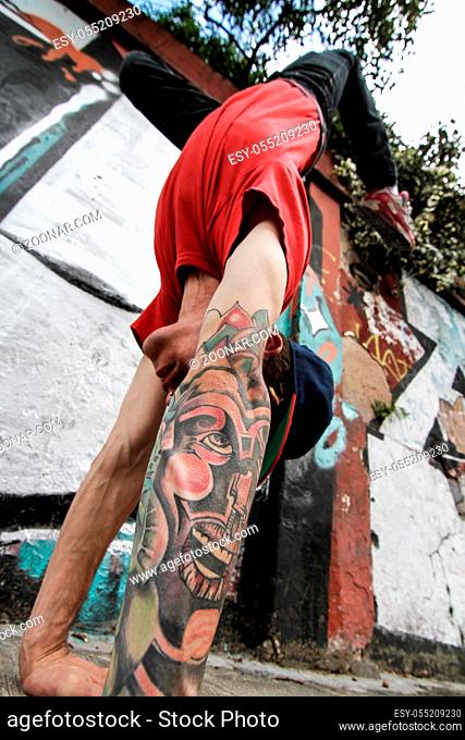 A performing hip-hop dancer in front of a graffiti wall