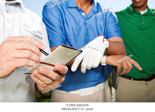 Golfer standing with friends writing in golf score card
