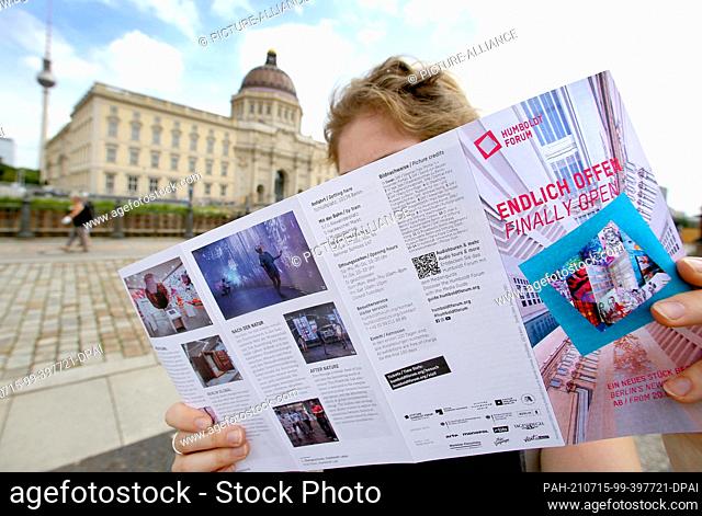 15 July 2021, Berlin: A young woman studies a brochure in front of the Humboldt Forum about the exhibitions on offer at the Forum's opening on 20 July