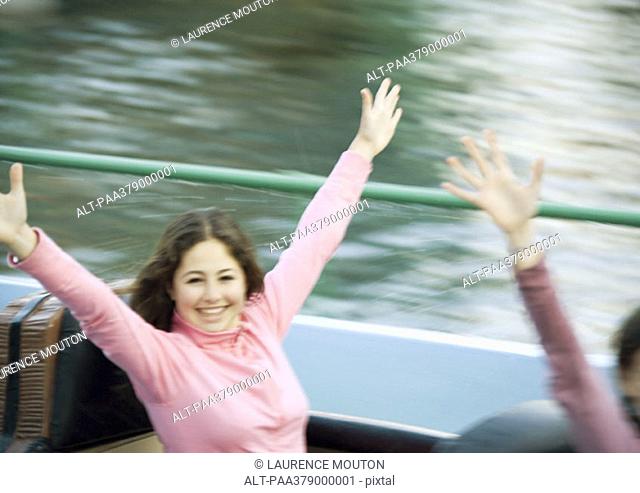 Teen girl on amusement park ride, arms in the air