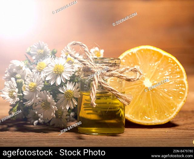 Lemon and chamomile essential oil on wooden background