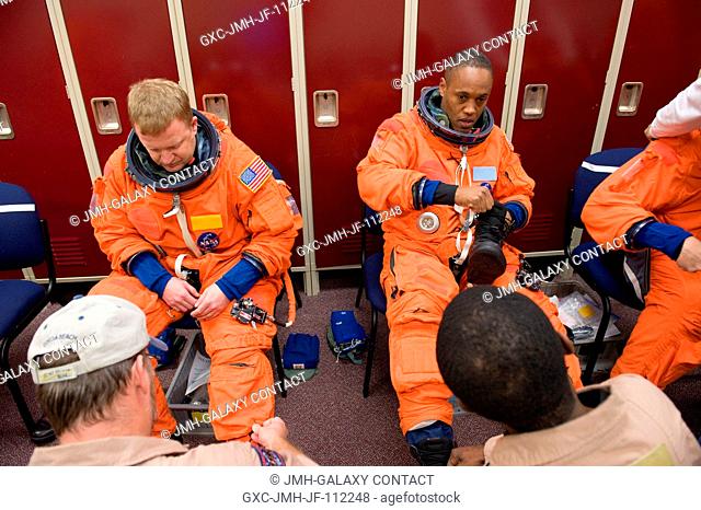 NASA astronauts Eric Boe (left), STS-133 pilot; and Alvin Drew, mission specialists, don training versions of their shuttle launch and entry suits in...