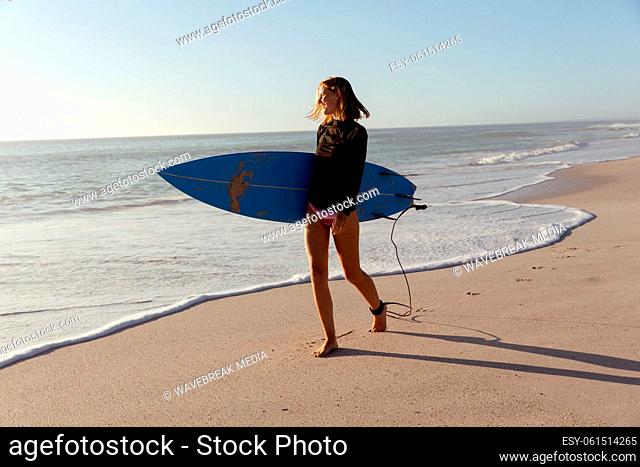 Woman with surfboard walking on the beach