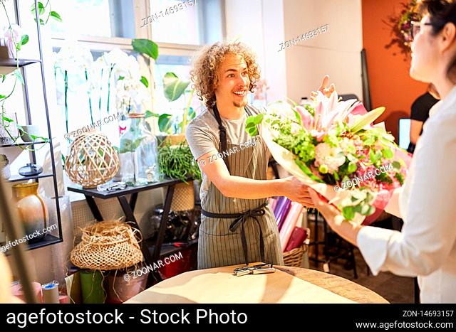 Florist im Blumenladen verkauft einen bunten Blumenstrauß an Kundin
