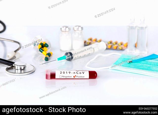 Blood test tube with the Coronavirus disease for virus test and research. Blood test tube with protective masks, medicines, thermometer