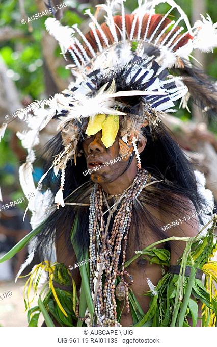Warrior adorned for a ceremony, with elaborate feather headdress and necklaces of shells. Kwato Island near Samarai Island, Milne Bay Province, Papua New Guinea