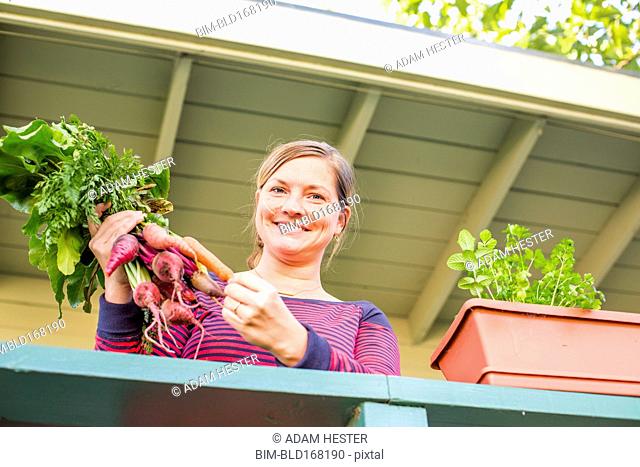 Caucasian woman holding fresh carrots on patio