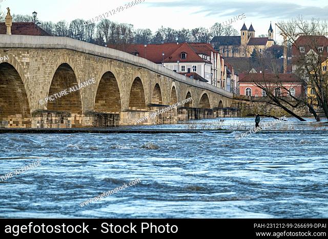 12 December 2023, Bavaria, Regensburg: The Danube is flooding near the Stone Bridge. According to experts, the danger of flooding along some Bavarian river...