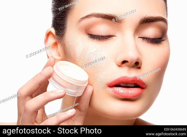 Beautiful young woman holding jar with loose powder near face. Closed eyes. Macro. Isolated over white background. Copy space