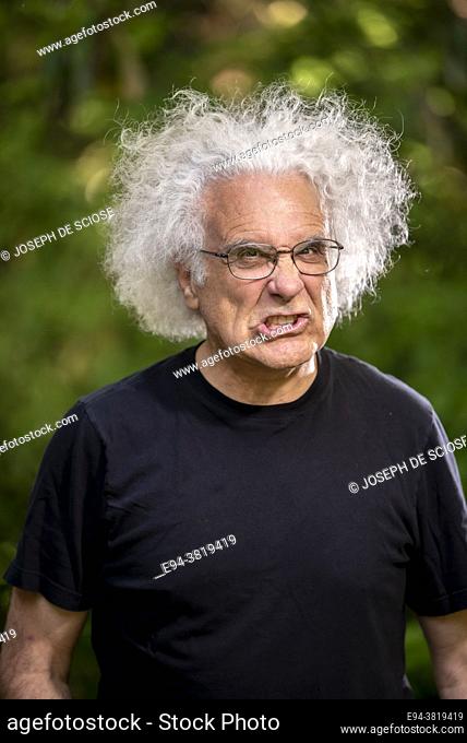 A grey haired 68 year old man making a face at the camera