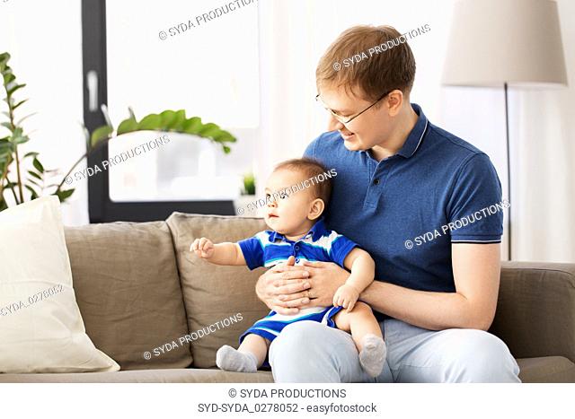 happy father with baby son sitting on sofa at home