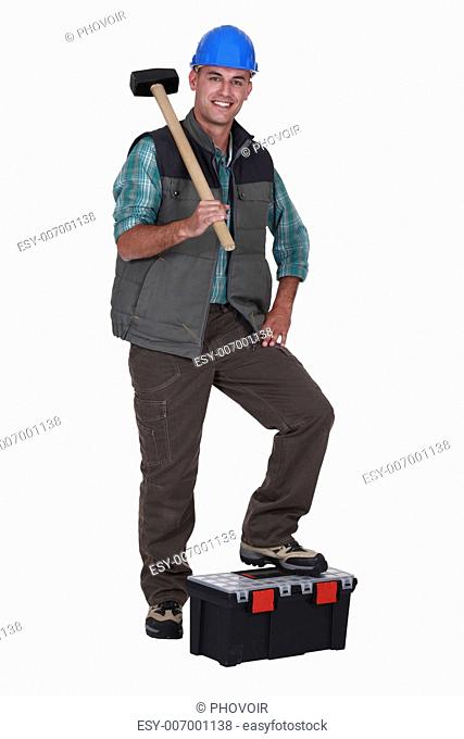 Man with sledge-hammer resting foot on tool-box