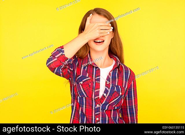 I'm not watching. Portrait of ginger girl in shirt covering eyes with hand and standing with open mouth, being surprised scared don't want to look