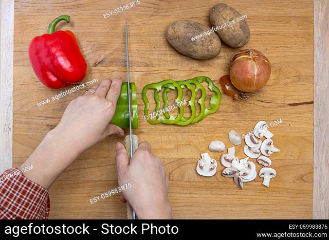 The act of cutting assorted vegetables on a cutting board