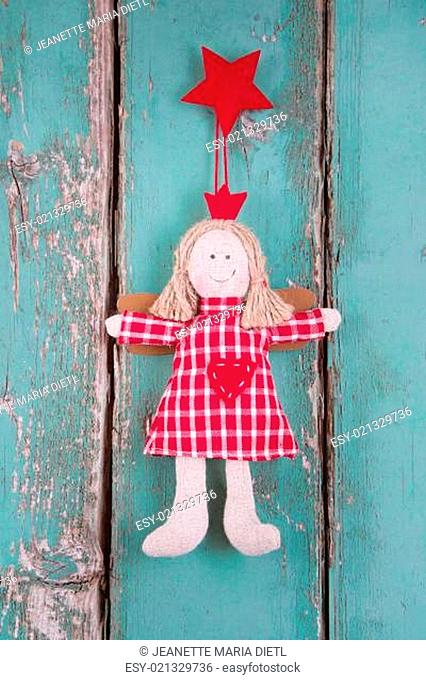 Sewn angel doll hanging on turquoise wooden background for christmas