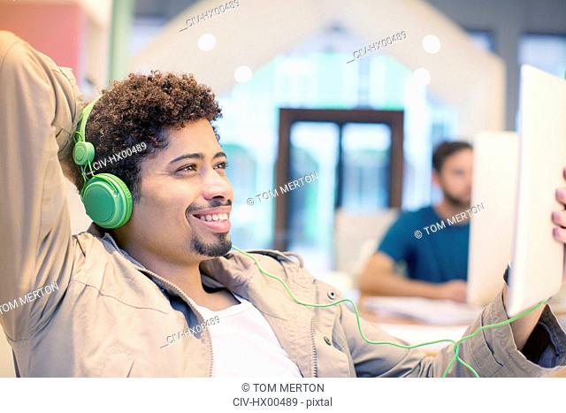 Creative businessman listening to headphones and using digital tablet