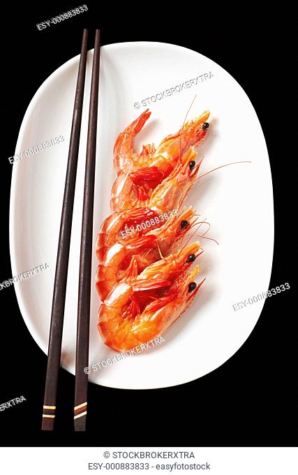 Image of tasty shrimps lying in row with two chopsticks near by