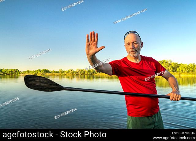 senior male with a stand up paddle on a calm lake in summer afternoon scenery, Fort Collins, Colorado