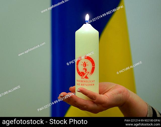 14 December 2022, Hamburg: Iryna Tybinka, Consul General of Ukraine, holds up the Peace Light from Bethlehem in front of the Ukrainian flag after the handover...