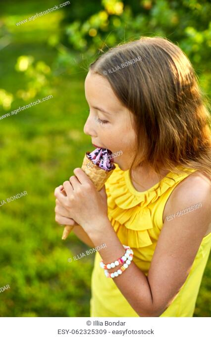 Happy girl with braces eating italian ice cream cone smiling while resting in park on summer day, child enjoying ice cream outdoor, happy holidays, summertime