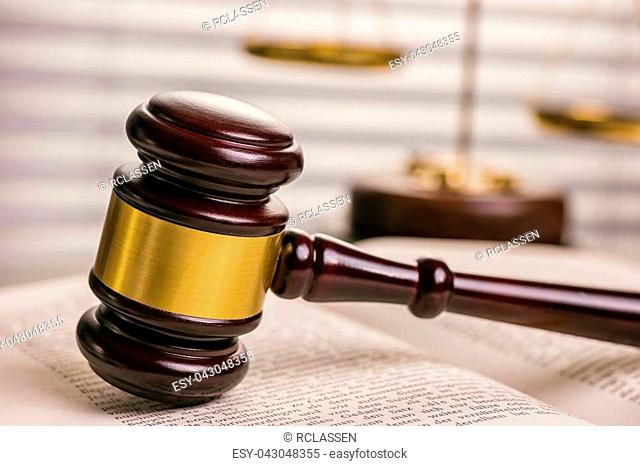 View of a wooden gavel on a tabel with justice scale in the background in a lawyer office. ideal for websites and magazines layouts