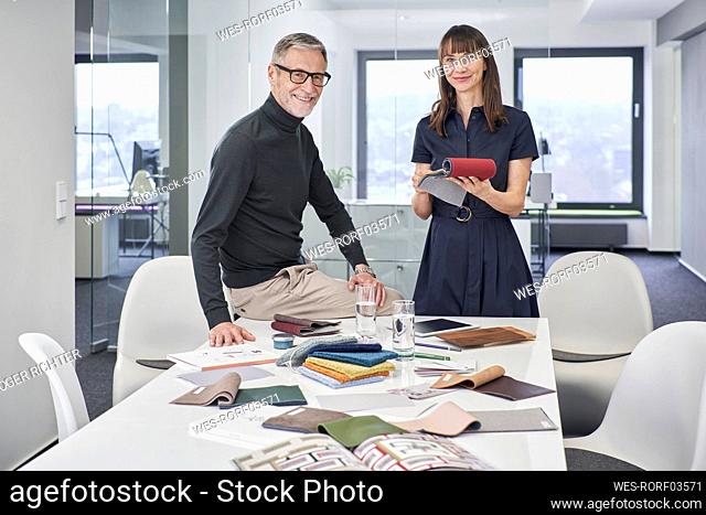 Portrait of smiling creative businessman and businesswoman with swatches in office