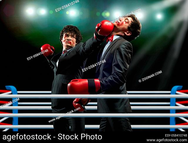 Two businessman in boxing gloves in ring fighting with each other