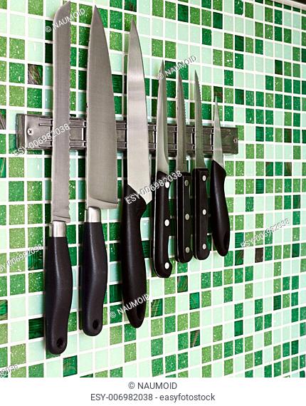 Kitchen knives on green mosaic wall