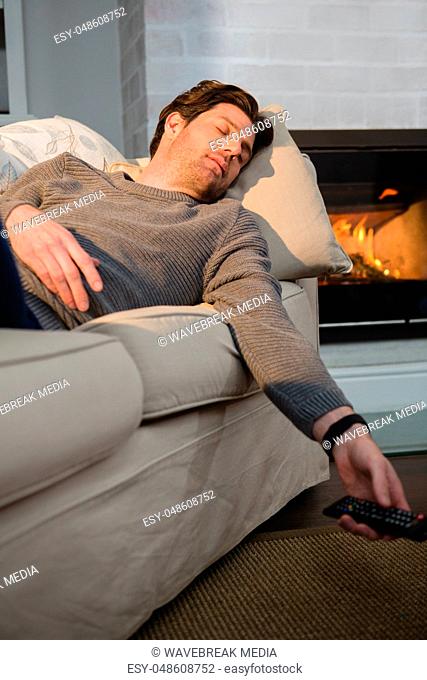 Man sleeping on sofa while watching television in living room