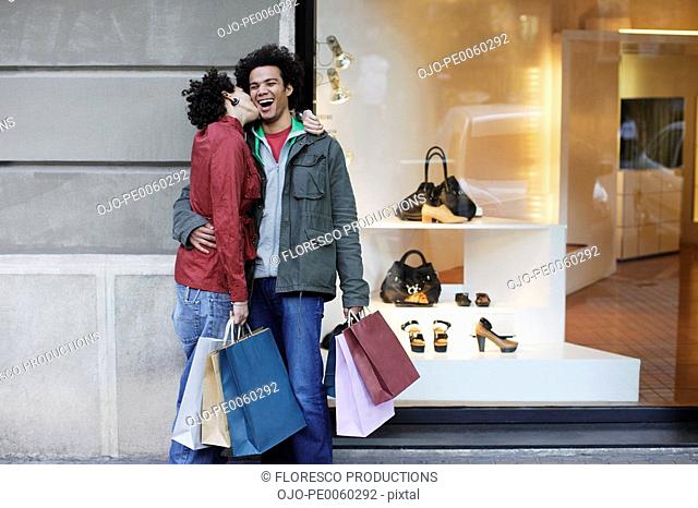 Couple outdoors with shopping bags kissing