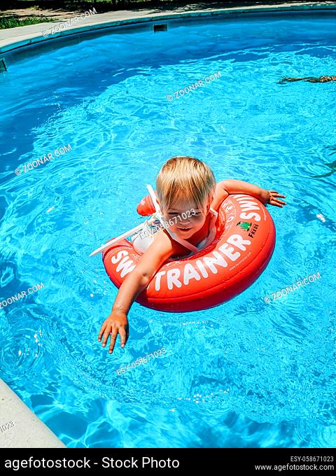 A small child swims in the pool on an inflatable swimming ring