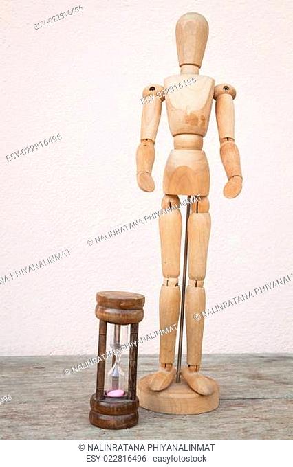 Wood mannequin and hourglass to represent time over