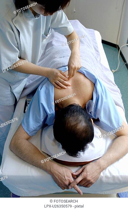 Young woman placing moxa on man's back