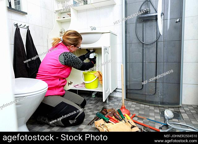 Female plumber repairing bathroom sink