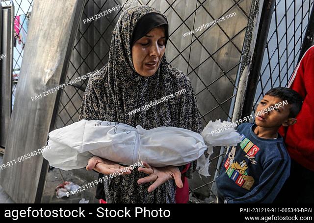 19 December 2023, Palestinian Territories, Rafah: A Palestinian woman carries the wrapped body of a her infant, killed in Israeli bombardment