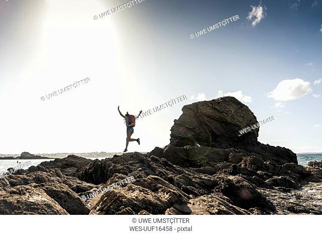 Young woman runnning and jumping on a rocky beach