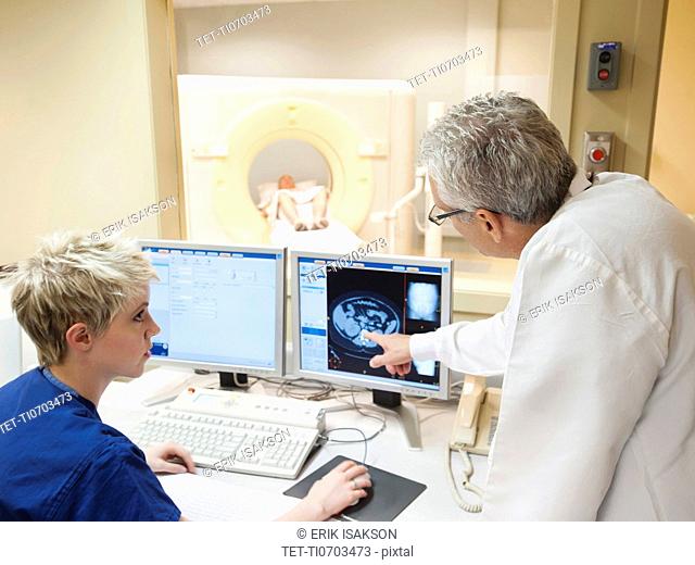 Doctor and nurse looking at CAT scan of patient's brain