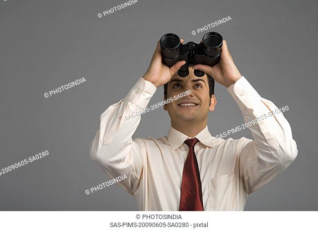 Businessman looking through binoculars