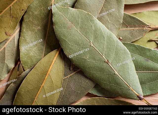 Dry bay leaves spilled on wooden board
