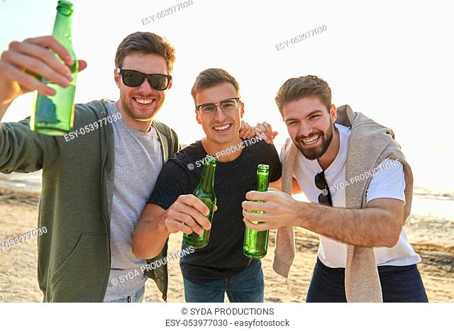 young men toasting non alcoholic beer on beach