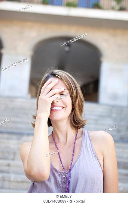 woman covering her eyes smiling