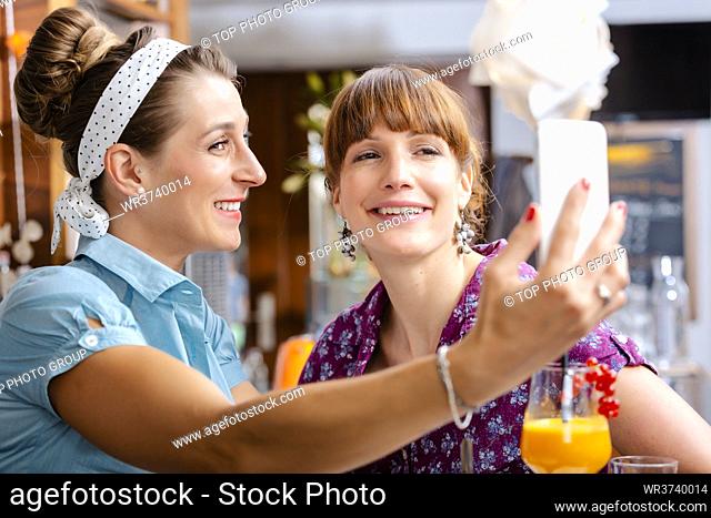 Two smiling women taking selfie on mobile phone