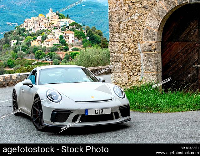 Supercar sports car Porsche GT3 in tight curve of historic track section of Rally Monte Carlo 1965, in the background La Roquette-sur-Var